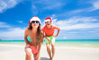 © el.rudakova - young couple in santa hats laughing on tropical beach. new year