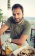 © Antonio Gravante - Young man sitting at the restaurant near the sea.