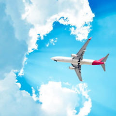 Canvas Print - Airplane flying in sunny sky with clouds