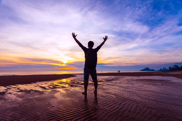 Man Raising His Hands  when sun rising up at sea beach