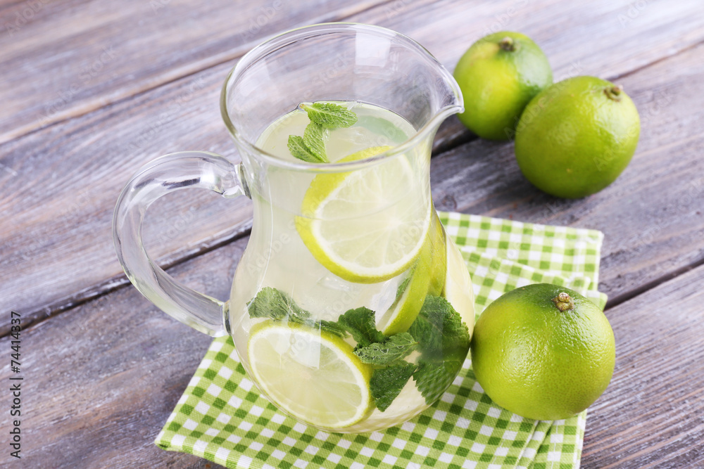 Lemonade in pitcher on wooden background