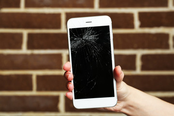 Canvas Print - Broken iPhone in hand on brick background