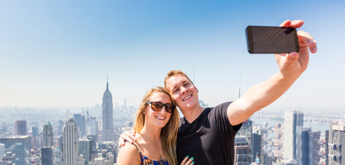 Wall Mural - Young Couple Taking Selfie with New York on Background