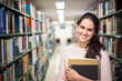 In the library - pretty female student with books working in a h