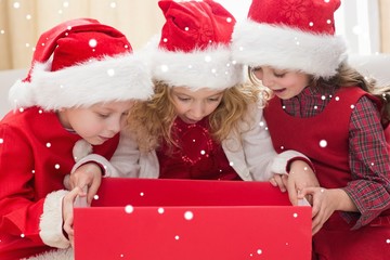 Composite image of festive little siblings looking at gift