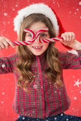 Happy little girl in santa hat holding candy canes