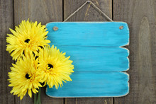 Blank Antique Blue Sign With Yellow Flowers Hanging On Door