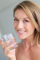 Portrait of blond woman holding glass of water