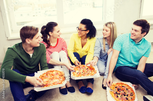 Photographie five smiling teenagers eating pizza at home