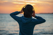 © Alex Photo - Woman in headphones enjoying sunset over the sea