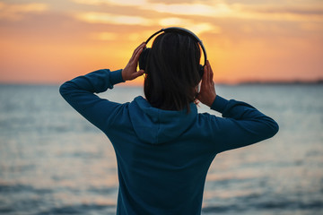 Sticker - Woman in headphones enjoying sunset over the sea