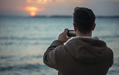 Wall Mural - Man takes photographs sunset over the sea