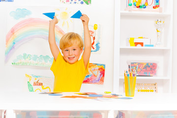 Blond cute boy learning shapes holding triangles