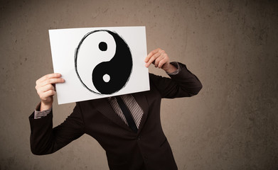 Wall Mural - Businessman holding a paper with a yin-yang on it in front of hi