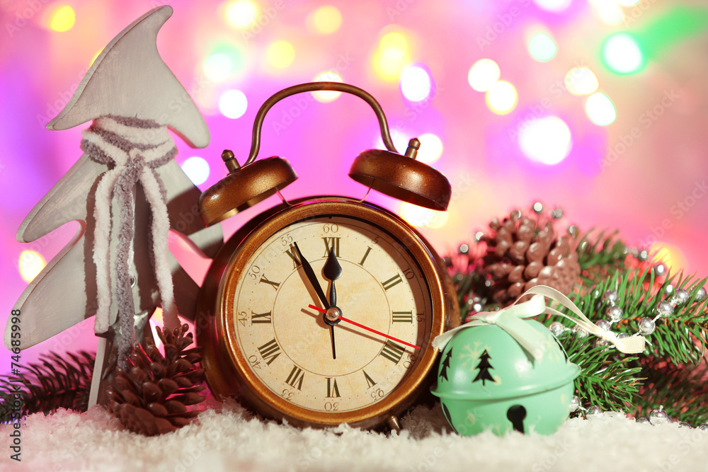 Alarm clock with Christmas decorations on bright background