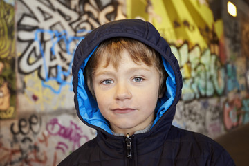 young boy in front of a colorful graffiti wall