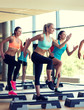 © Syda Productions - group of women working out with steppers in gym