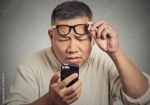 Fotografía Hombre con gafas que tiene problemas para ver la pantalla del teléfono
