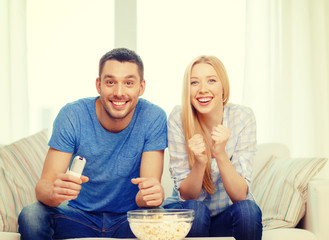 Wall Mural - smiling couple with popcorn cheering sports team