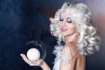 Snow Queen with frozen makeup holding a snowball