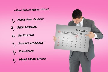 Poster - Composite image of businessman pointing at calendar in his hands