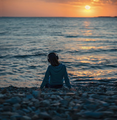 Poster - Girl in headphones sitting on beach on sunset