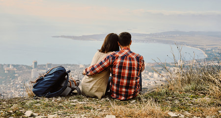 Wall Mural - Couple in love sitting on hill and looking at the city