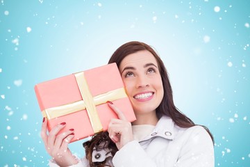 Poster - Composite image of portrait of a happy brunette holding gift