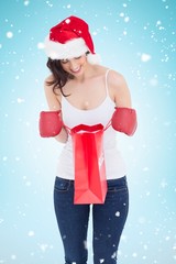 Poster - Happy brunette in boxing gloves looking in shopping bag