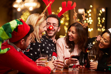 group of friends enjoying christmas drinks in bar