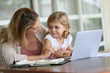 © goodluz - Little girl looking at laptop computer with her mom