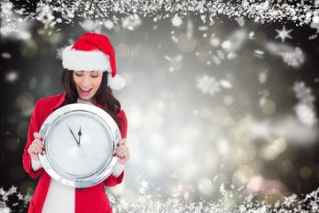 Poster - Composite image of excited brunette holding a clock