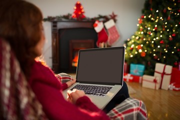 Rear view of redhead using laptop at christmas