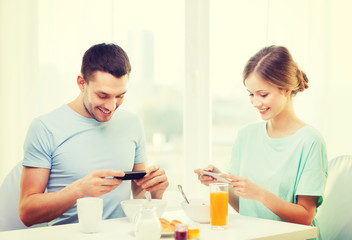 Canvas Print - smiling couple with smartphones taking picture