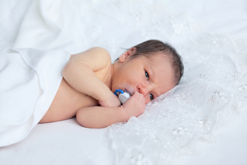 Wall Mural - Cute newborn boy girl with baby's dummy on background of white l