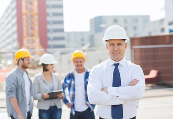 Canvas Print - group of smiling builders in hardhats outdoors