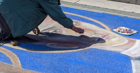 artist paints with colorful chalks on the street image of saints