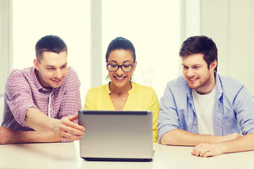 Canvas Print - three smiling colleagues with laptop in office