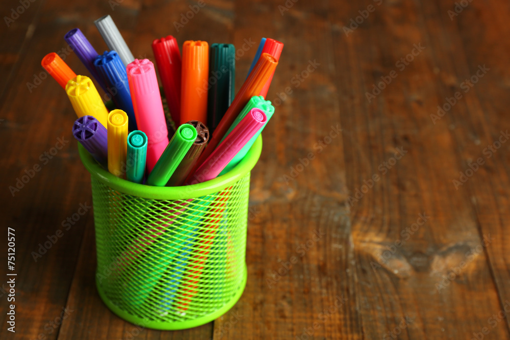 Colorful markers in metal holder on rustic wooden background
