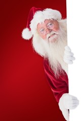 Poster - Composite image of santa looks out behind a wall