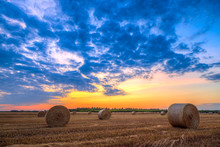 Sunset Over Farm Field With Hay Bales