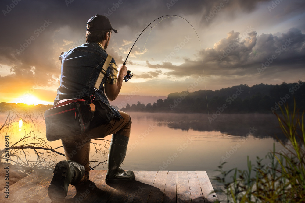 Young man fishing at misty sunrise - obrazy, fototapety, plakaty 
