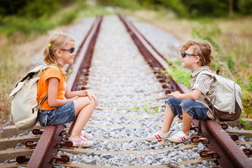 Wall Mural - two little kids with backpack sitting on the railway