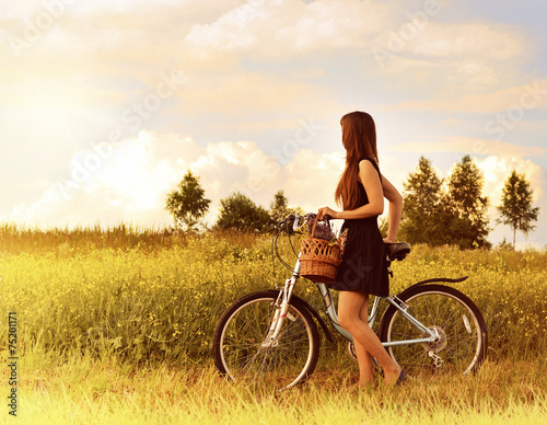 Naklejka ścienna beautiful girl riding bicycle in a grass field