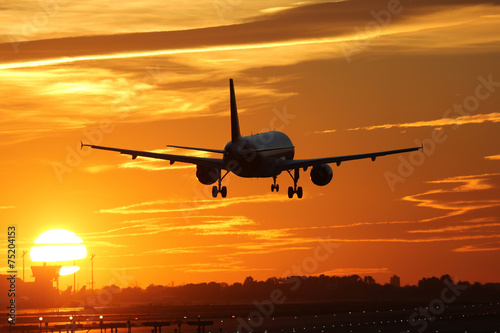 Fototapeta na wymiar Flugzeug beim Landen auf Flughafen mit Sonnenuntergang