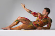 © theartofphoto - Muscular man, skin painted with Holi colors, laying on the floor