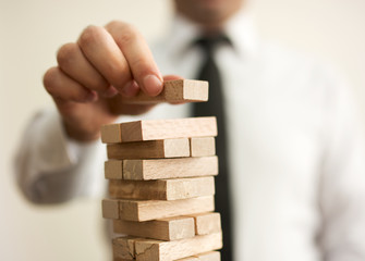 Businessman putting last block to the tower