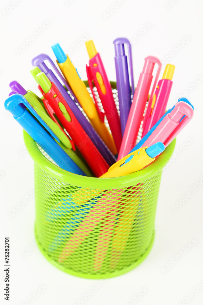 Colorful pens in green metal vase isolated on white background