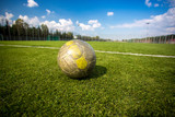 Fototapeta Sport - shabby soccer ball lying on artificial grass field