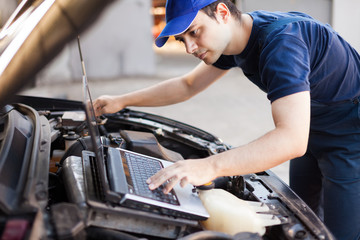 mechanic using a laptop computer to check a car engine